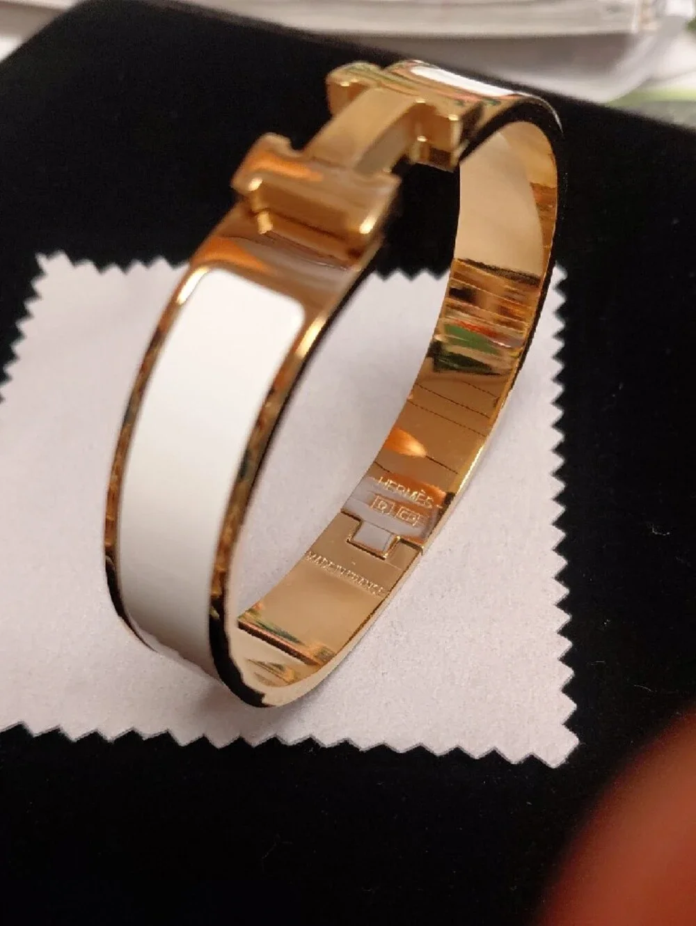HERMES Gold and White Enamel Click H Bracelet with Signature H Accent.